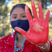 View of Native American woman with the palm of her hand painted red